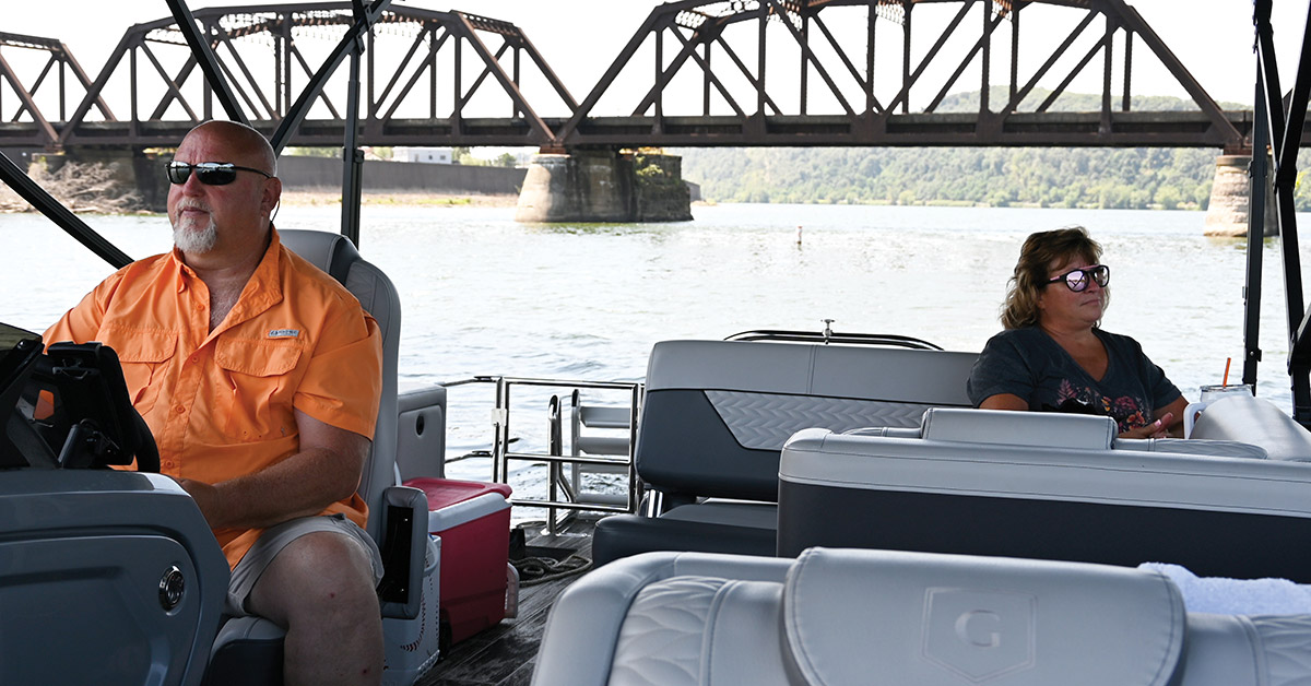 Al Razzis in driver's seat of pontoon while Laura Goodman-Jenkins sits in the back
