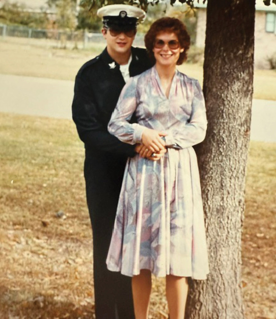 Vintage photo of a man in uniform standing with a woman beside a tree.