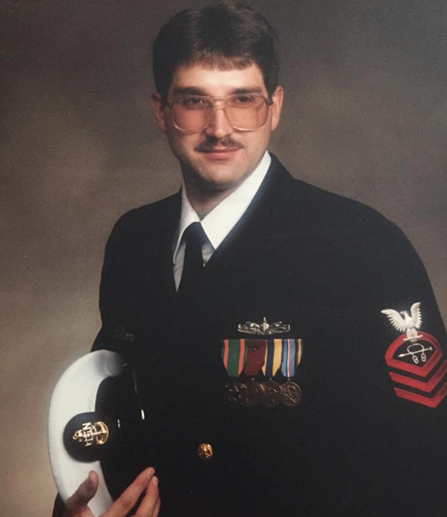Military portrait of a man with glasses holding a uniform cap.