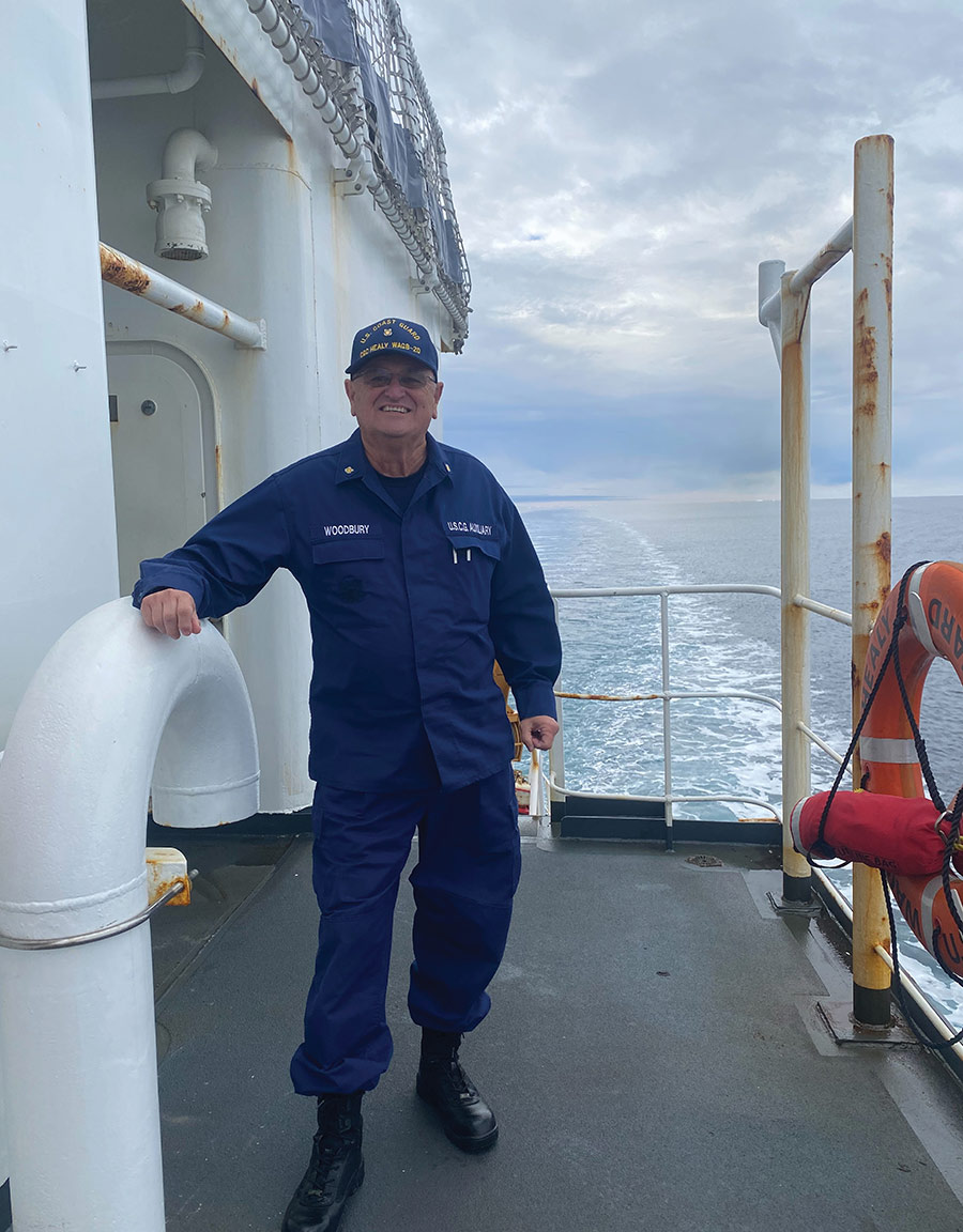 A smiling man in a Coast Guard Auxiliary uniform stands on a ship deck.