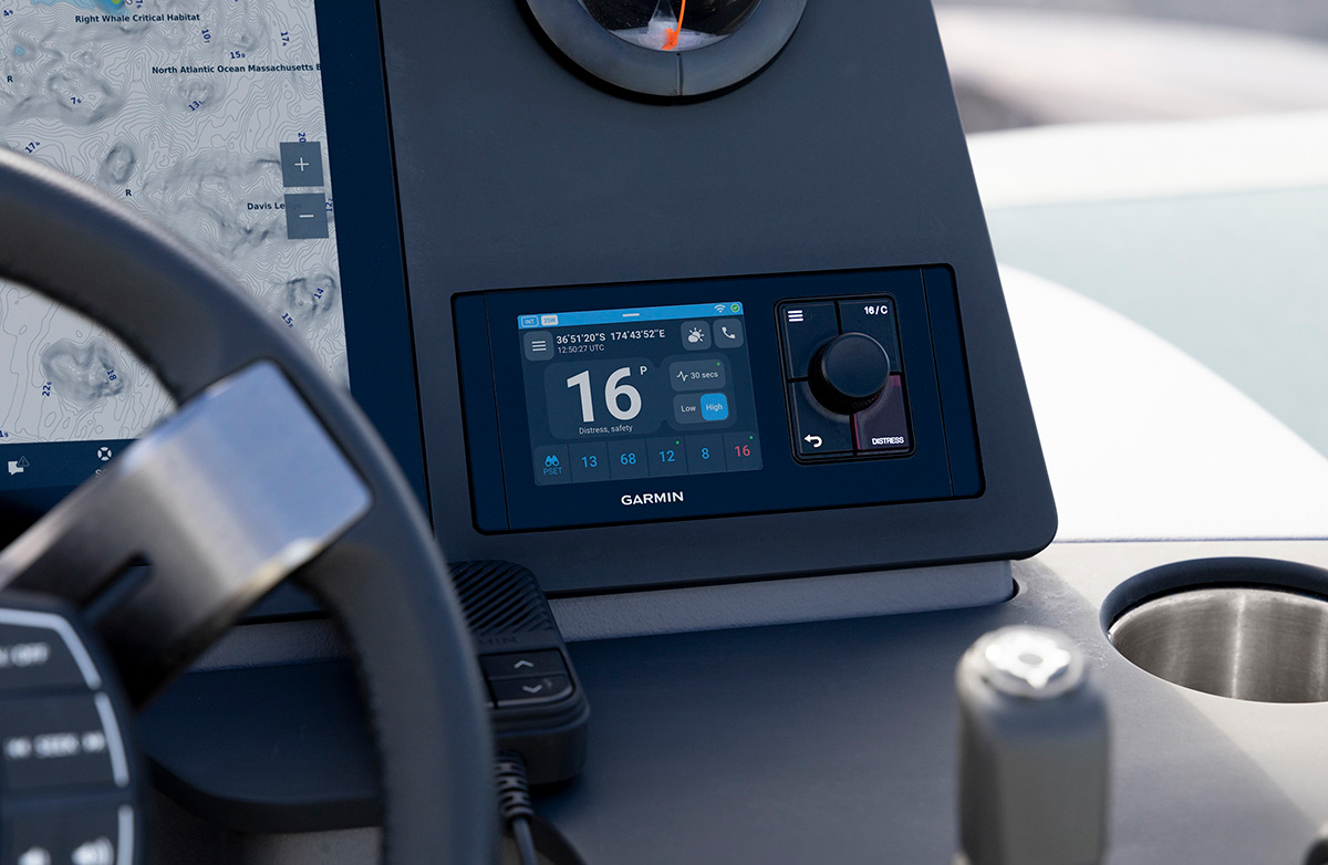 A Modus marine audio receiver interface. The screen displays FM 102.7 next to a signal icon. A large control knob on the left features a blue light ring, matching a row of backlit playback and setting buttons along the bottom.