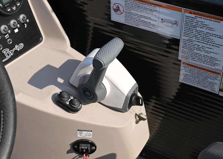 A grey and white throttle lever on a boat console next to warning labels.