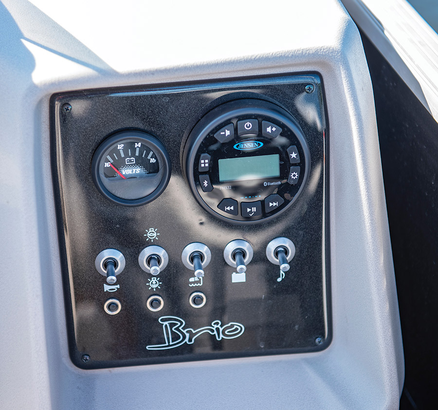 A close-up view of a boat dashboard control panel featuring a voltmeter, a Jensen stereo, and toggle switches.