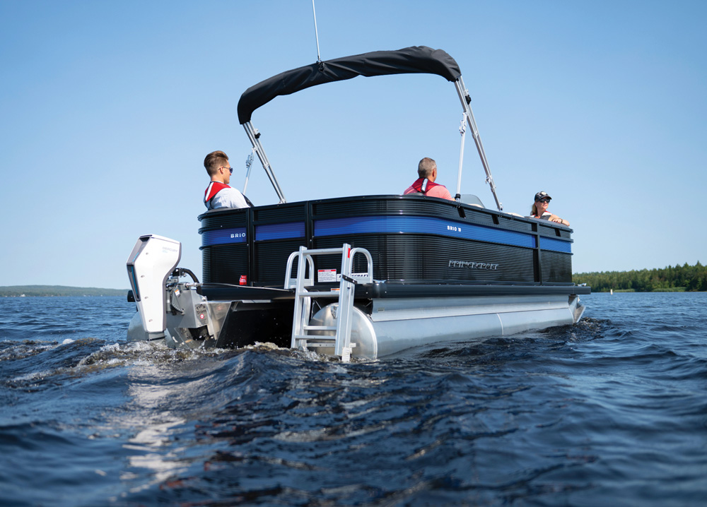 Rear view of a Princecraft Brio electric pontoon boat with three passengers cruising on a lake.