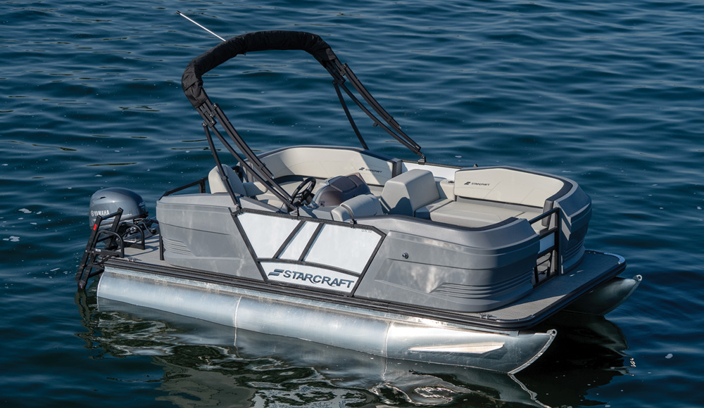 An empty grey Starcraft pontoon boat with an electric motor docked on deep blue water.