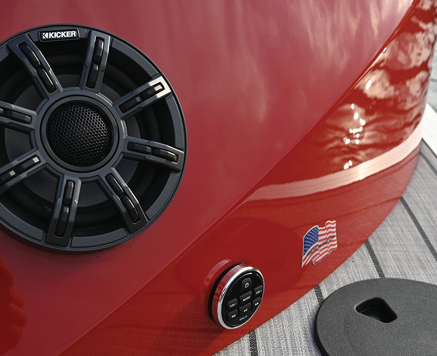 A close-up of a Kicker speaker and remote control mounted on a red boat panel.