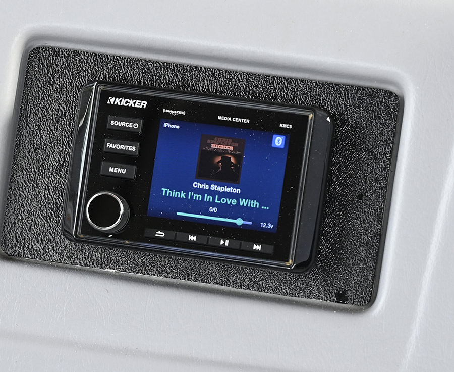 A digital Kicker media center display mounted on a grey boat dashboard.