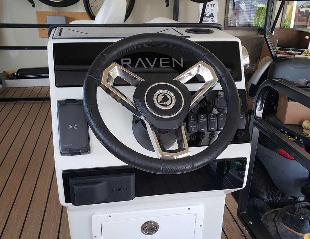 A modern white Raven steering console with a leather-wrapped wheel and digital controls.