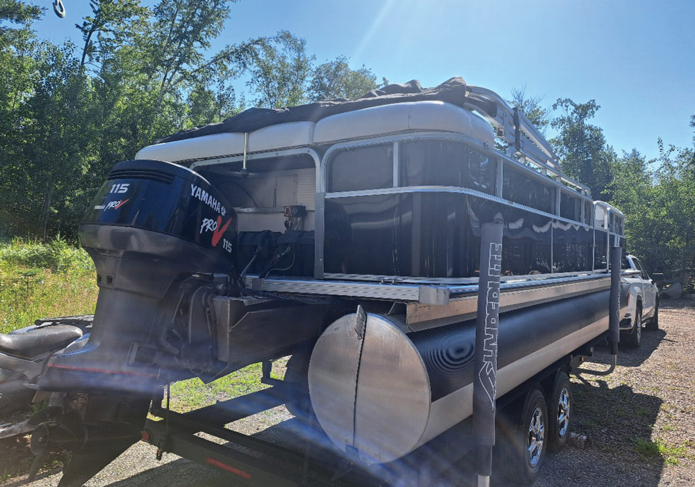 Close-up rear angle of a Yamaha Pro V 115 motor mounted on a black pontoon boat trailer.