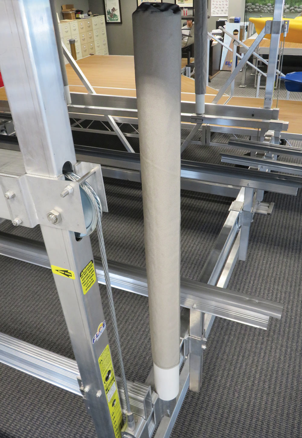 Close-up of an aluminum boat lift frame showing the steel cable pulley system and vertical padded guide post.