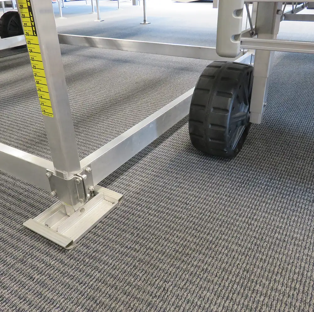 Detailed view of a boat lift frame base showing the aluminum foot pad, measuring ruler, and black wheel.