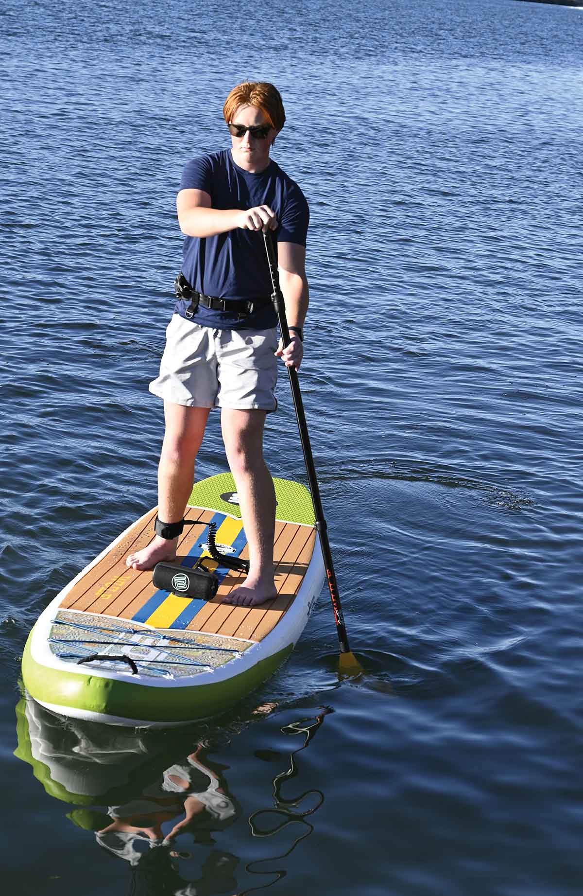 Person paddleboarding on calm blue water with a BOTE Wulf paddle board.