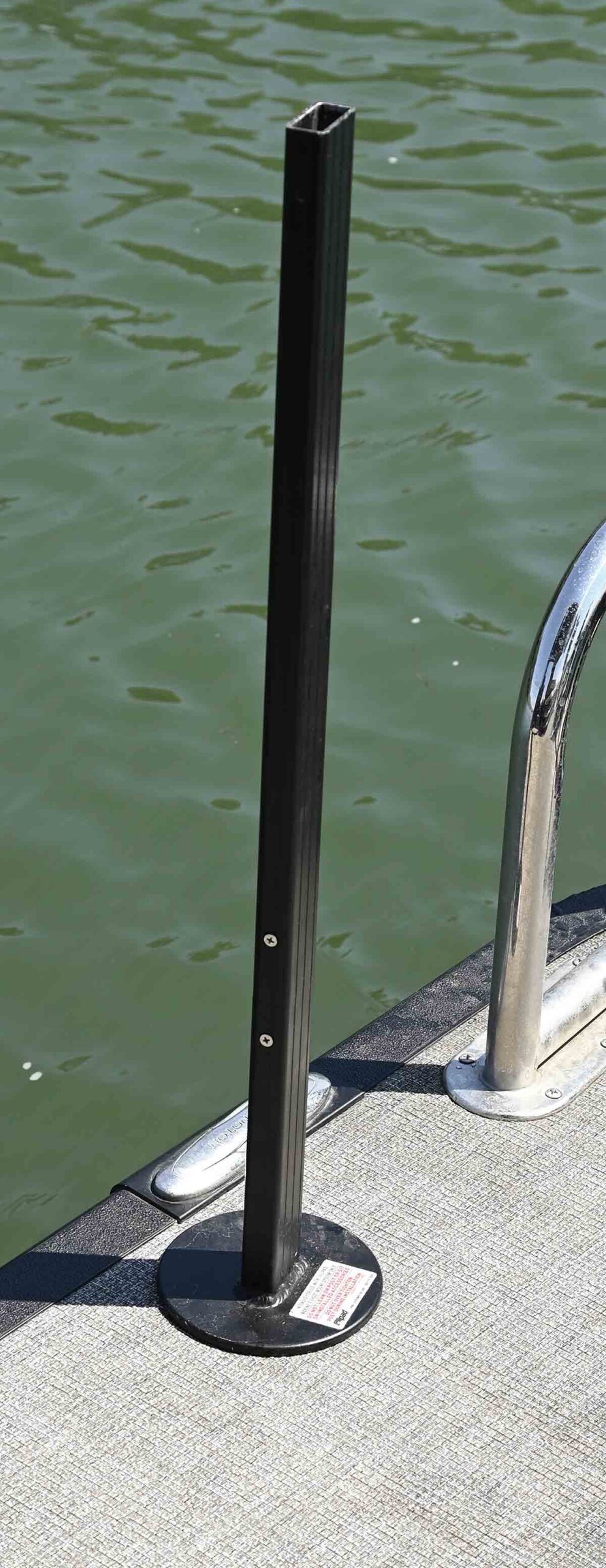 Black metal mounting post for a grill installed on a pontoon boat deck.