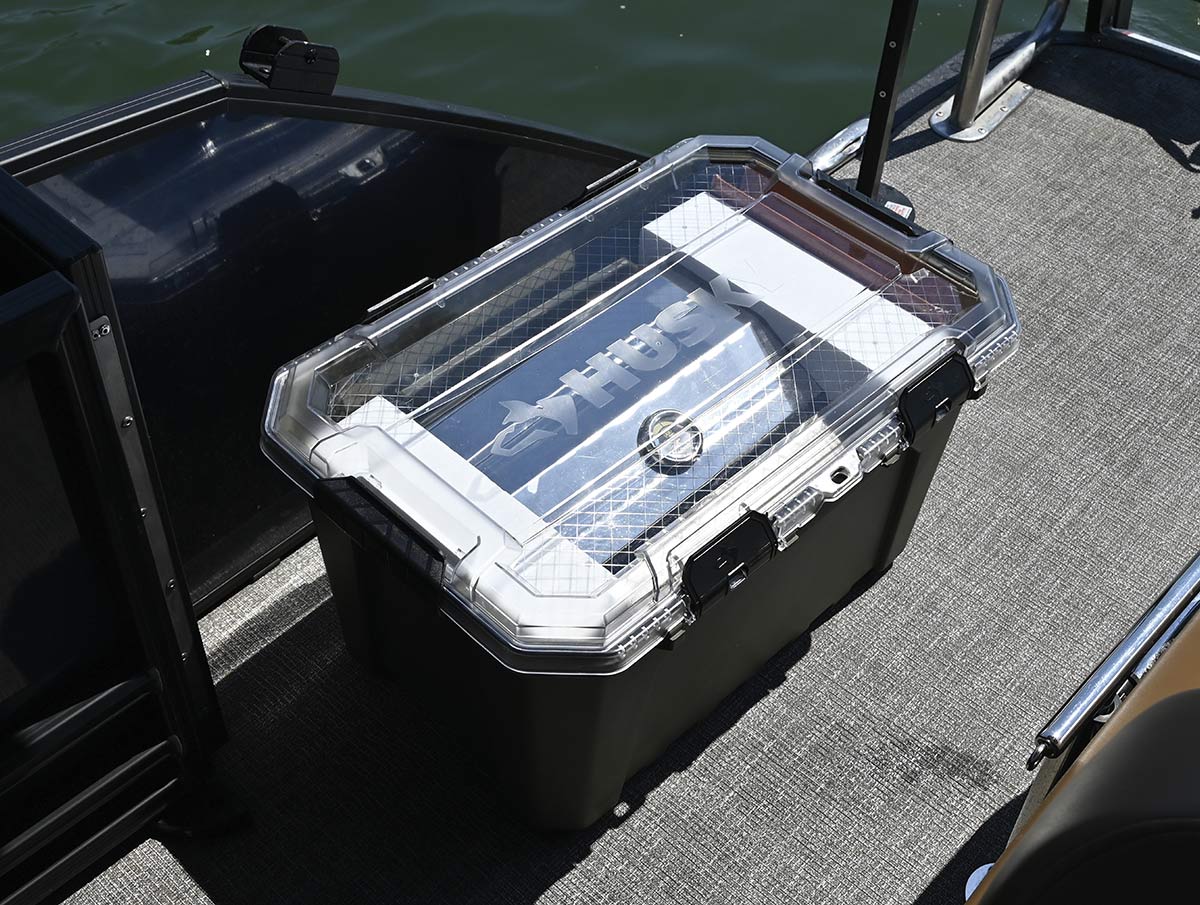 Husky hard-shell storage case sitting on the carpeted deck of a boat.