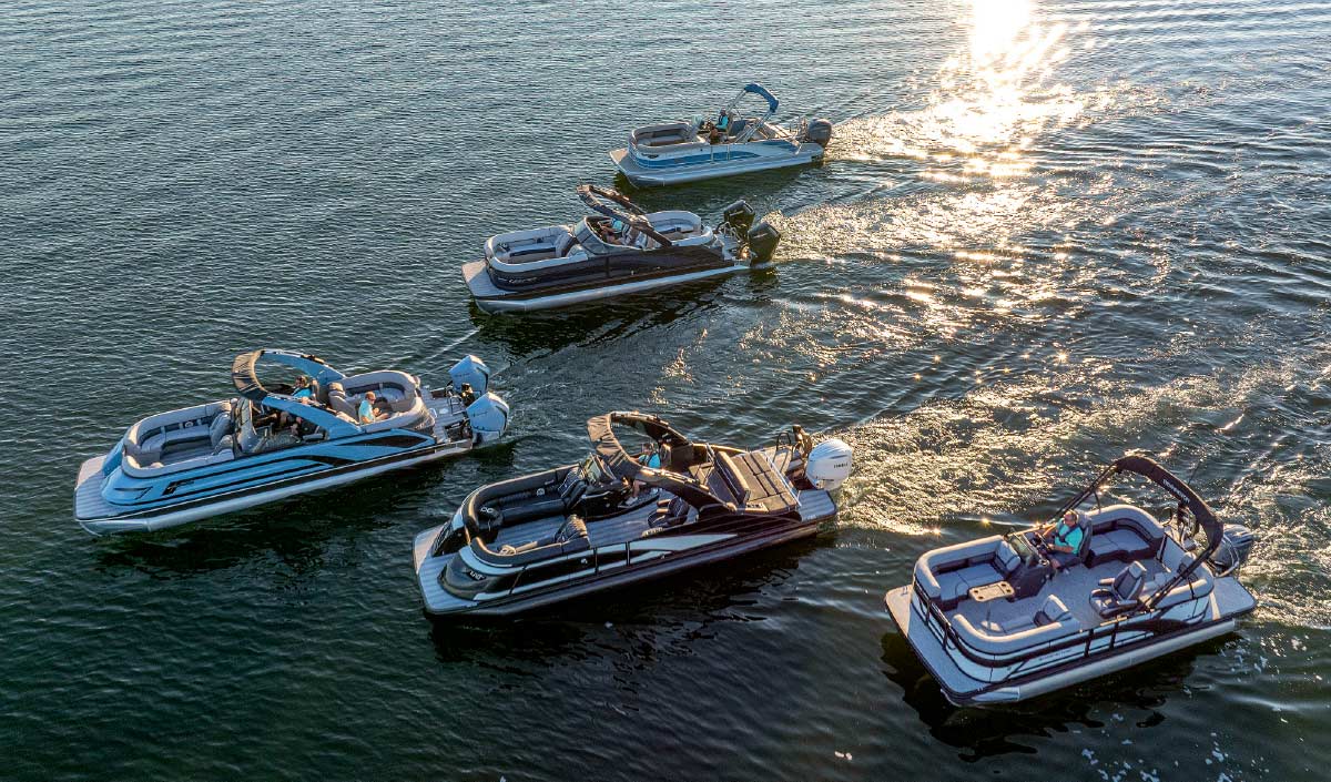 High-angle aerial view of five pontoon boats cruising together on open water.