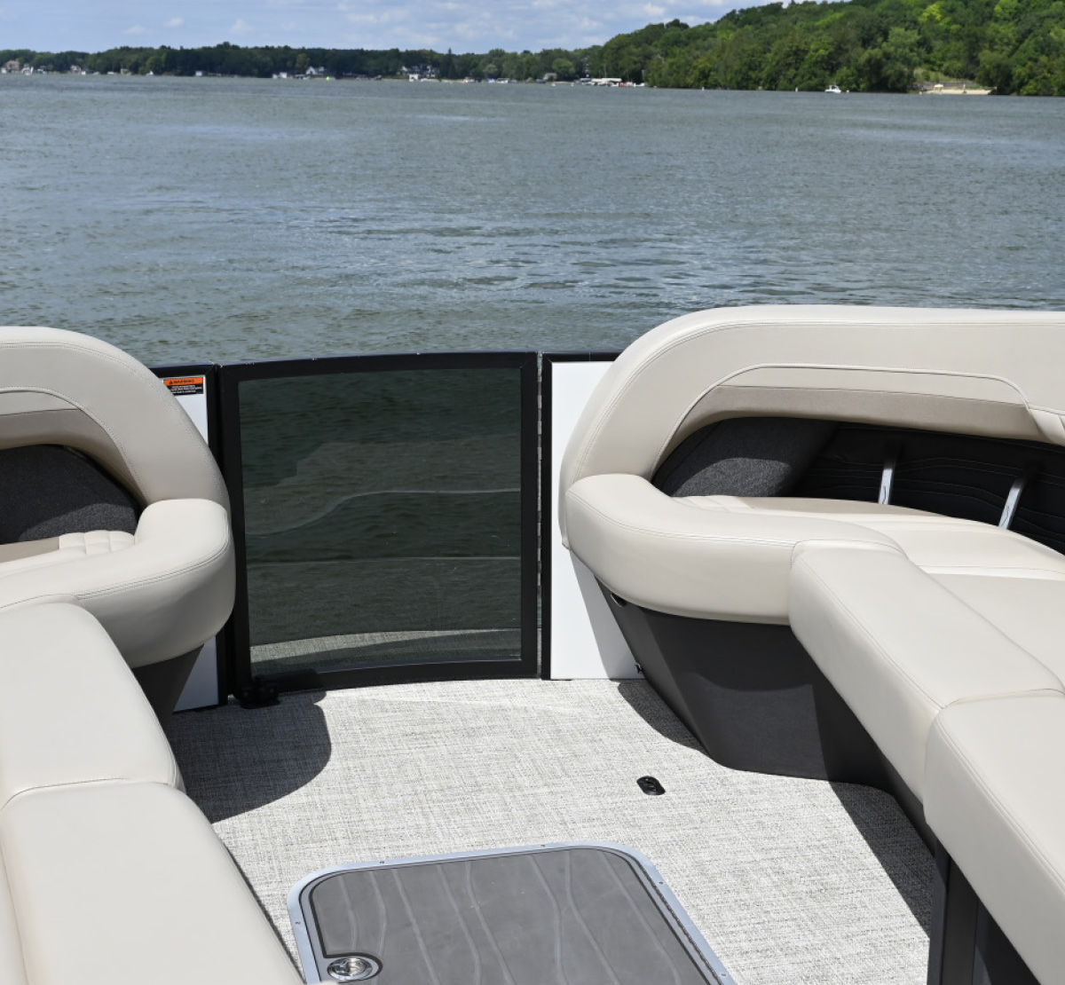Interior view of plush cream pontoon boat seating with a dark tinted safety gate facing the water.