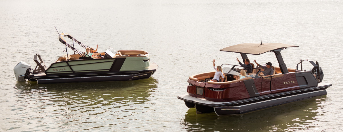 Two Revel pontoon boats anchored on calm open water with passengers waving.