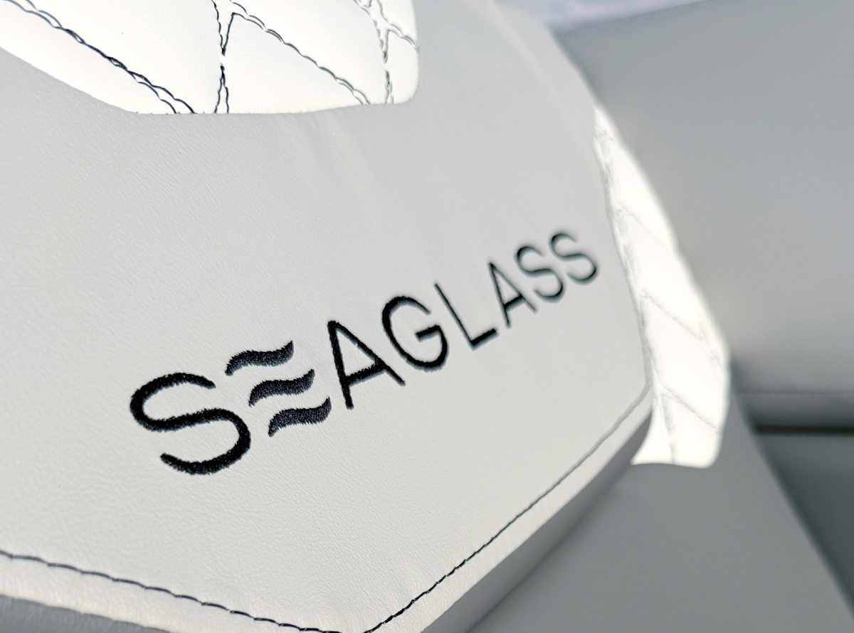 Close-up of black embroidered "SEAGLASS" text on white quilted leather marine upholstery.