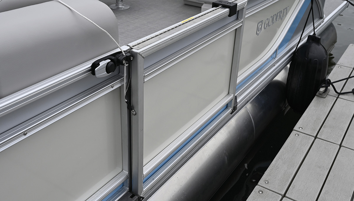 Side door of a Godfrey pontoon boat docked securely alongside a wooden pier.