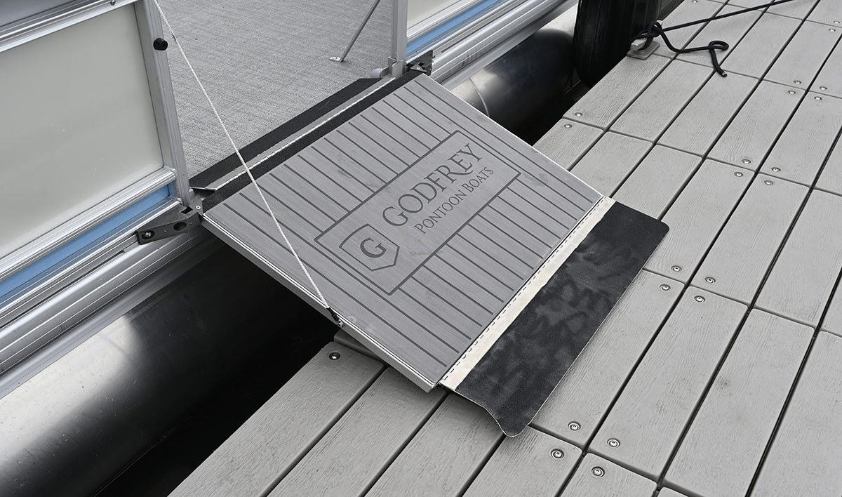 Godfrey Pontoon Boats fold-down side boarding ramp extended onto a wooden dock.